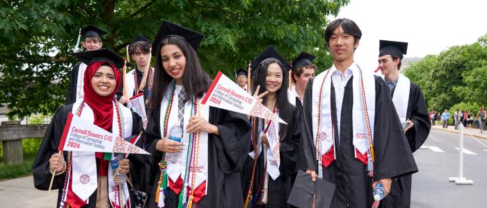 Cornell CIS graduates pose with Bowers flags.