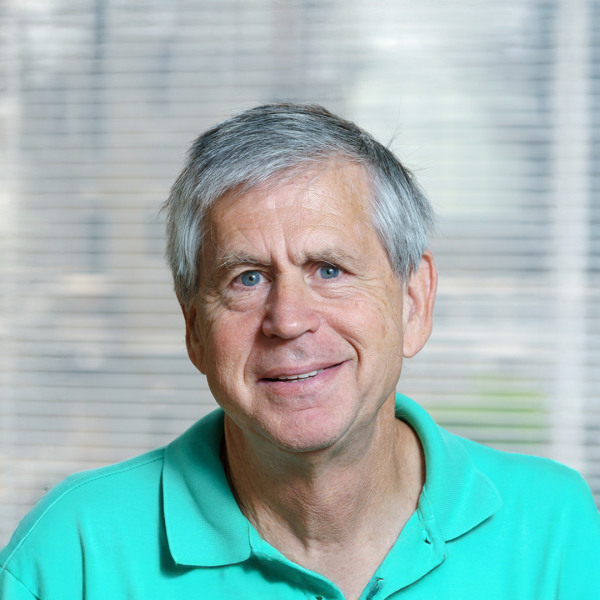 A color photo of a man in front of a window.