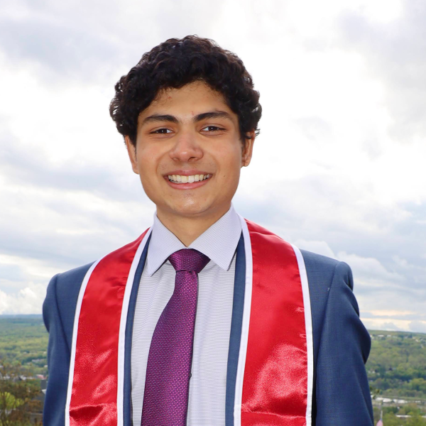 A color photo of a man smiling for a photo outdoors.