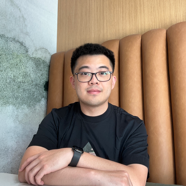 A color photo of a man with glasses sitting in a restaurant booth.