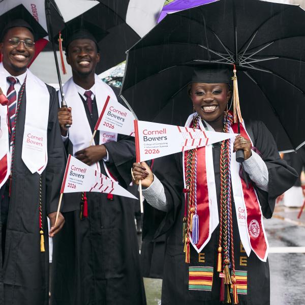 a group of graduates smile under their umbrellas during the procession