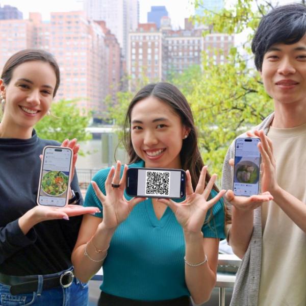 Three students looking at camera holding up phones to show their apps