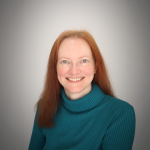 A color photo of a woman smiling for a photo.