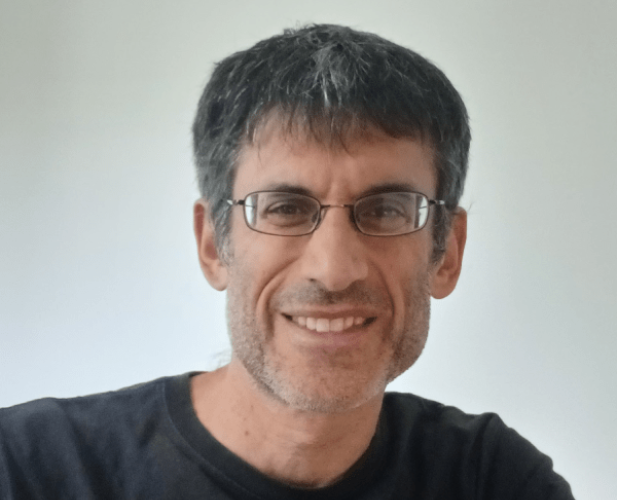 A photo of Robert Kleinberg, a smiling man with short gray hair, glasses and a black shirt in front of a gray background