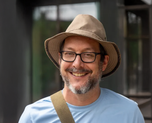 A photo of David Bindel, a man in glasses, a brown hat and blue tshirt