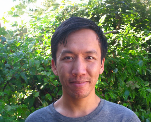 A photo of Justin Hsu, a man with short dark hair in front of a leafy background
