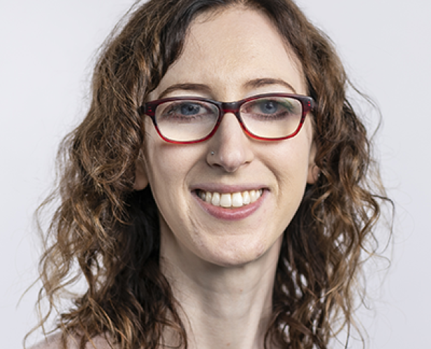 Women with glasses, curly hair, smiling at camera