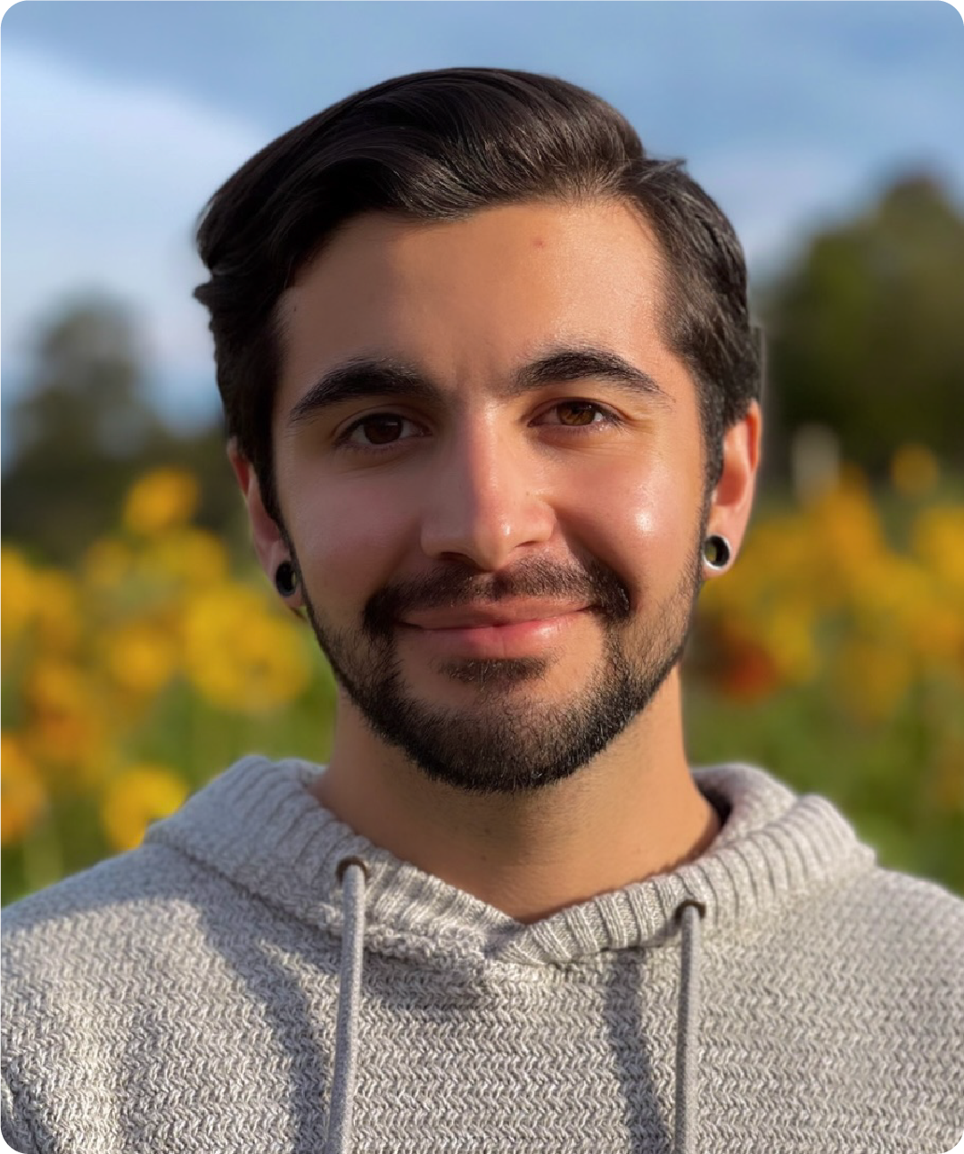 A color photo of a man smiling for a photo outside.